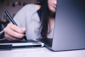Girl at her desk with a laptop and writing notes in a notepad