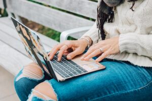 A young girl sitting on a bench on her laptop