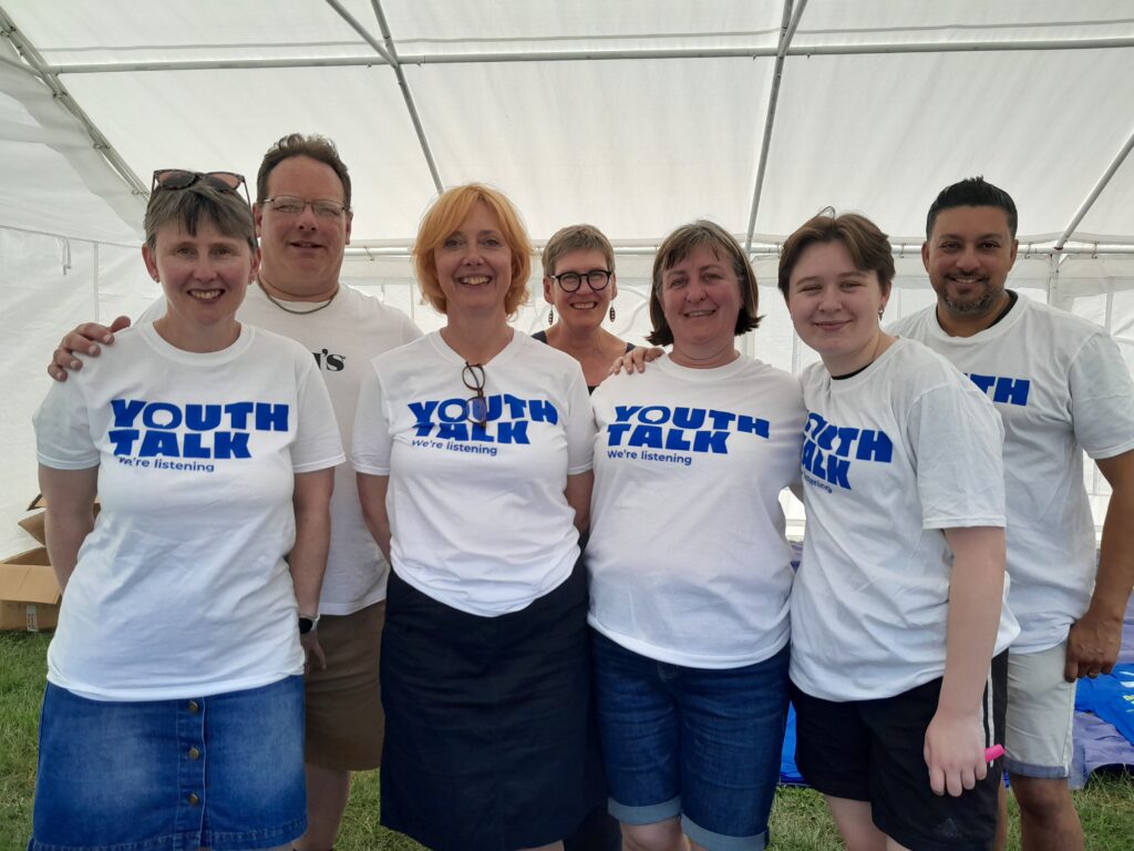 A group of volunteers wearing Youth Talk t-shirts smiling for a picture at the St Albans Half Marathon.