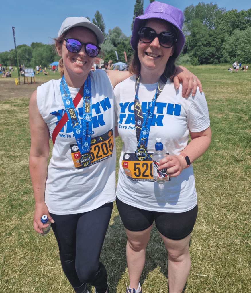 Dawn and a friend smiling for a picture during the St Albans Half Marathon wearing Youth Talk t-shirts.